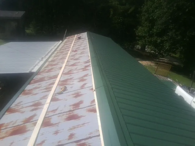 Old rusted panels beside newly installed green metal roofing — Wind Damage Roof Repair by Roofing Brothers in Euclid