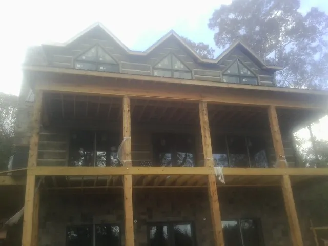 Dormers and porch framing on a large log home under construction — Roof Coating work by our crew in Euclid
