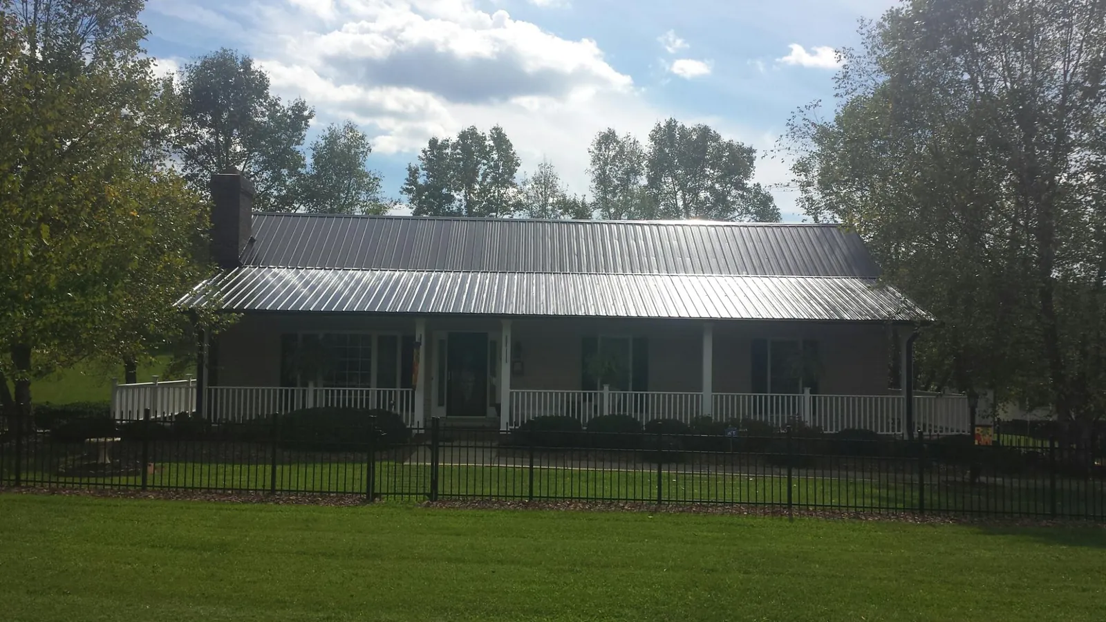 Gray metal roof on a brick ranch with a full width front porch — Gutter Guard Installation work by our crew in Euclid