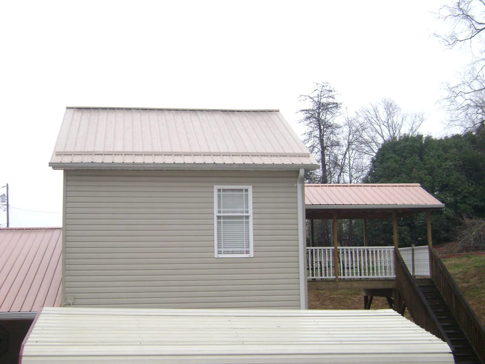 Tan metal roofs on a two story addition and attached porch, from a Roof Replacement job in Euclid